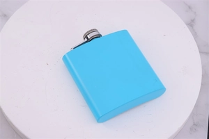 Overhead view of a sleek blue 6oz stainless steel hip flask on a white round tray