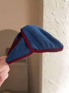Macro shot of denim fabric triangular hair clip with detailed burgundy edge stitching