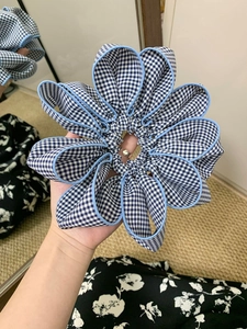 Detail of blue gingham fabric scrunchie with layered flower design and elastic hair tie