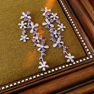 Macro detail of silver flower tassel earrings with purple crystals and sparkling zircons