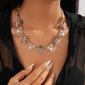 Detailed view of vintage gold necklace with pink resin flowers and crystals on a model