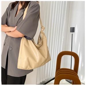 Minimalist cream hobo tote bag worn over shoulder in a stylish indoor setting