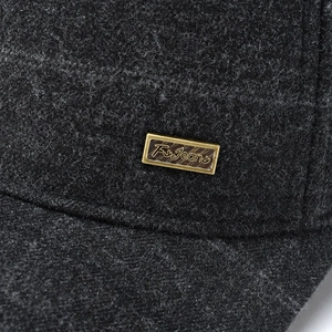 Detail of wool fabric texture and rectangular bronze metal logo on winter cap side