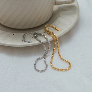 Detailed shot of gold and silver stainless steel oval bead bracelets on ceramic decor