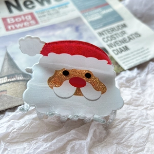 Close-up of a festive Santa Claus hair claw clip with red hat and glittery details