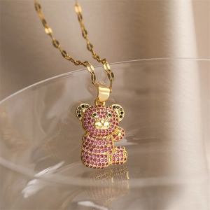 Close-up of golden necklace with a pink and black gemstone-encrusted teddy bear pendant