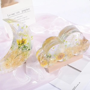 Detailed view of moon and cloud resin bookends with dried flowers and pearl accents