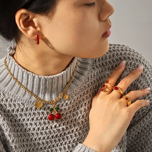 Close-up of luxury gold jewelry set with red zircon gemstones worn on a grey sweater