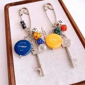 Creative safety pin keychain with mini tape measure, vintage key, and colorful dice charms