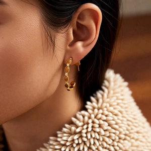 Détail de boucles d'oreilles C plaquées or 18 carats avec gemmes brunes et zircons