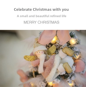 Detail of pink plush angel ornament with golden wings and feathers on a Christmas tree