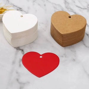 Macro shot of heart-shaped paper gift tags in white, brown, and red on marble surface