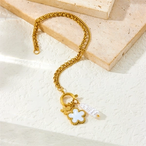 Golden double chain bracelet with white clover, butterfly and baroque pearl charms on stone