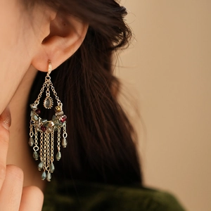 Macro shot of gold tassel earrings with colorful beads and zircon flowers on a model
