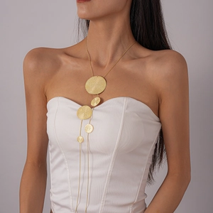 Macro detail of layered gold tassel necklace featuring hammered metal circular discs