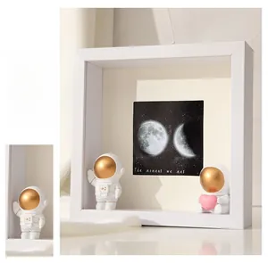 Deep white shadow box frame with astronaut figures and moon phase art display