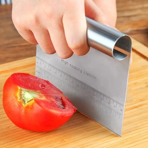 Stainless steel dough scraper with measurement scales used for cutting fresh tomatoes