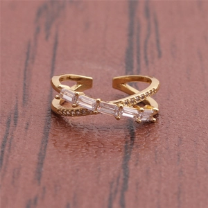 Detail eines vergoldeten Crossover-Rings mit rechteckigen und runden Zirkonia-Steinen