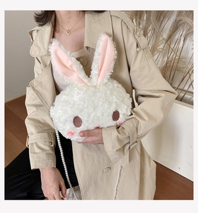 Detail of white plush rabbit bag featuring elegant pearl chain strap and soft faux fur texture