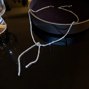 Detailed close-up of a silver bow necklace with sparkling zircons on a dark surface