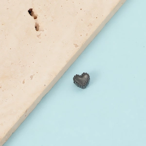 Macro view of a 1mm hole stainless steel heart pendant with scalloped edge detail