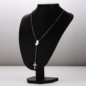 Silver and gold rosary necklace with face profile and crucifix pendant on display