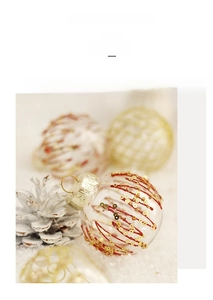 Close-up of PET Christmas ball with red glitter and gold sequins on a snowy pine branch