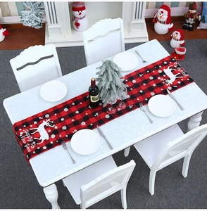 Detail van rood-zwarte geruite kersttafelloper met rendierprint en feestelijke tekst erop