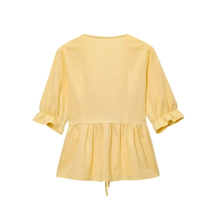 Detail of yellow peplum top with puffed short sleeves and pleated cuff texture