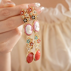 Detail of vintage gold earrings with cameo portraits and colorful floral rhinestones