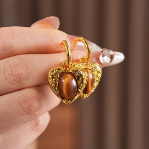 Close-up of vintage resin heart earrings with brown stone and small diamonds on model