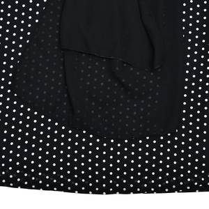 Detailed view of lightweight black chiffon fabric with classic white polka dot patterns