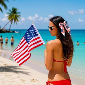 Woman on the beach wearing a USA flag bow hair clip and holding a small American flag