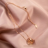 Detail of rose gold triple interlocking ring necklace on elegant satin fabric