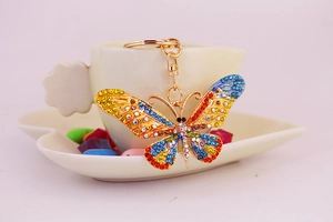 Macro shot of colorful crystal butterfly keychain with golden metal frame on white tray