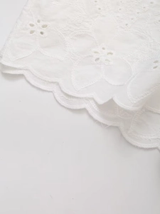 Macro shot of white cutout embroidery fabric with elegant scalloped edge detail