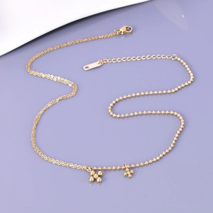 Close-up of gold beaded cross pendants on a polished stainless steel chain