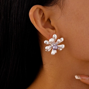 Vue détaillée d'une boucle d'oreille fleur argentée avec perle mauve sur un modèle