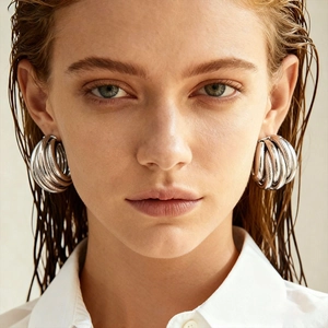Minimalist silver multi-layered geometric hoop earrings on female model with wet hair look