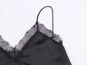 Close-up of intricate black lace trim on V-neckline of satin camisole top