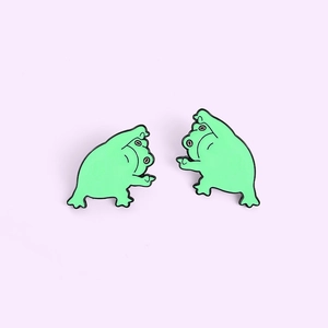 Détail de deux épingles en émail de grenouille verte créatives avec un geste drôle