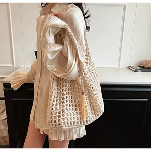 Detailed side view of beige crochet tote bag with fringe tassel on a female model