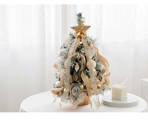 Mini tabletop snowy Christmas tree with golden star topper and festive ornaments