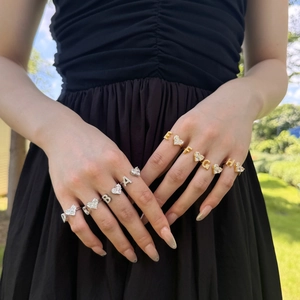 Close-up of gold and silver letter heart rings with sparkling zircon inlay on model