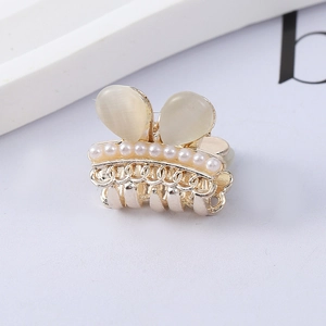 Detailed macro view of golden mini hair claw clip featuring opal stone and white pearls