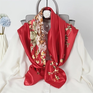 Red silk scarf with large beige and brown floral prints tied on a white shirt