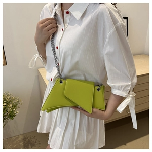 Detail of lime green geometric shoulder bag with asymmetric flap and silver chain strap