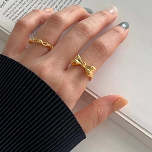 Detail of 925 sterling silver bow and chain rings on hand against a book background