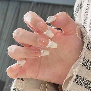 Close-up of pearl heart charms and resin details on short gradient press-on nails