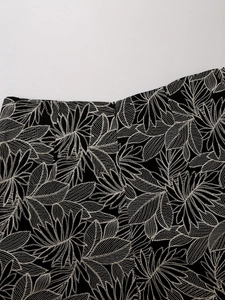 Close-up of leaf embroidery pattern on high waisted black fabric with zipper detail